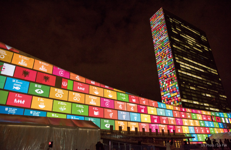 図版：2015年，SDGsが採択されたときの様子。国連本部の壁にプロジェクションマッピングで17のゴールが彩られた