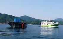図版：九島と宇和島港を結ぶフェリー。左は当社JVが据え付けた橋脚