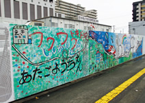 写真：事務所前の仮囲いには，幼稚園児が描いた新幹線の絵が。現場は地域の大きな期待を背負う