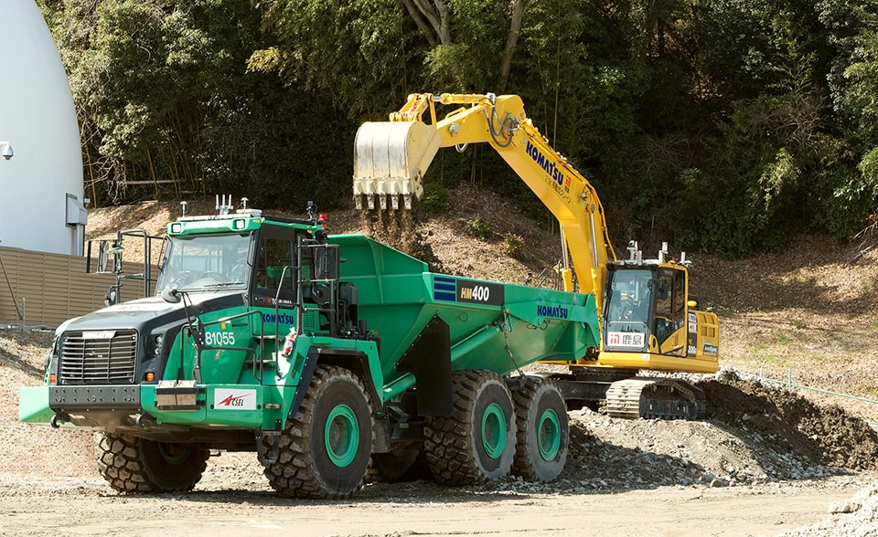 Automatic backhoe loading into an automatic articulated dump truck