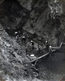 月ノ沢発電所（山形県）中心部埋戻し（右岸断層部突入）工事 昭和27（1952）年。雨なのか、蓑をつけ菅笠をかぶっている。