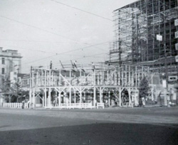 歩道の上に防護構台を建設中。昭和26（1951）年6月29日　右隣は協和銀行ビルを施工中。足場は丸太。