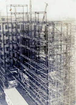鉄骨建方。　昭和27（1952）年4月8日。中央通を挟んだブリヂストンビルから撮ったものか。丸太の外足場と梁鉄骨のフィーレンデールがよく見える。