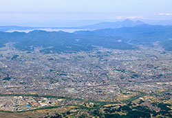 福島県郡山市（2012年撮影）。市街地の外側に安積疏水によってできた緑の穀倉地帯が広がり、その先に猪苗代湖がみえる（写真提供：郡山市）