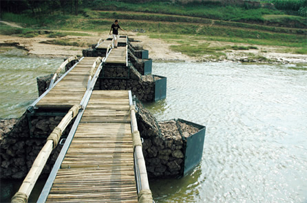 写真：新しい橋。蛇籠の橋脚，V字の鉄板，竹の床と手すりによって，水の抵抗を軽減させたデザイン