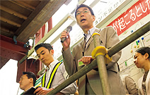 写真：朝礼台に立つ東京ステーションホテルの藤崎さん（現総支配人）。左が山本さん