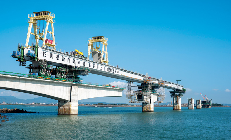 図版：全長318.8mの架設桁によるセグメントの運搬。橋形クレーンでセグメントを吊って架設地点まで運搬する（2020年10月）