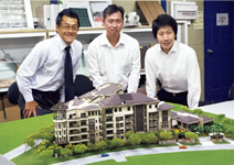写真：全体模型を前にスタッフと森重豪雄KOAプロジェクトディレクター（左）