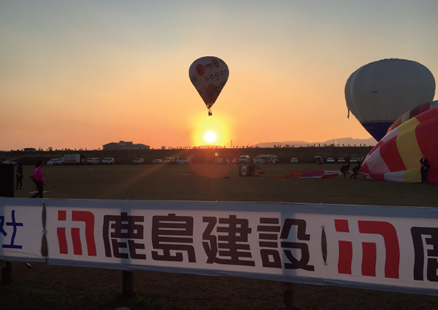 写真：夕陽を浴びるバルーンと当社の横断幕（増村さん撮影）