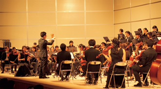 写真：指揮をする松井工事課長代理とオーケストラ