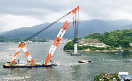 図版：据付け場所へ橋脚を曳航する「海翔」。巨大橋脚も小さく見える