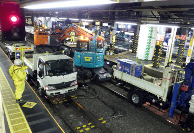 図版：夜間工事で軌陸式の工事用車両が並ぶ駅構内（現場撮影）