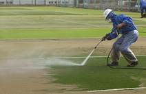 写真：テニスコートの砂を高圧水洗浄で集めていく