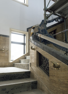 図版：階段サイドの壁は沖縄産の石，手摺はバリアフリー基準に則った高さと強度で真鍮手摺（転用）と復原手摺を追加