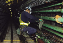 写真：内径が小さいため鋼製のセグメントでトンネルを構築する四日市坑内では，屈んで作業