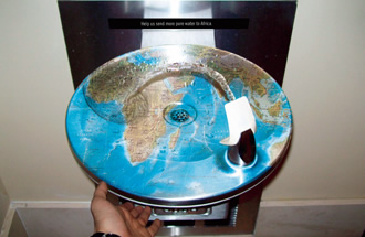 写真：受け皿に世界地図がプリントされたウォータークーラーは，ボタンを押すとちょうどアフリカの位置に水が落ちるようにデザインされている。アフリカへの給水設備の設置を呼びかけるしかけ