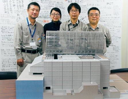 写真：燃料取り出し用カバーが設置された3号機の模型と肥田泰明 工事長、宮崎美穂 職員、加藤和宏 工事長、菊池 淳 計画長