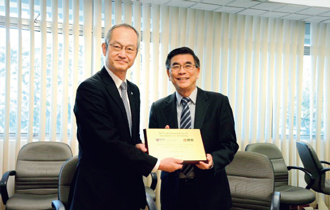 写真：写真はラム・キー・ポー学部長と当社技術研究所・福田孝晴所長による署名式の様子