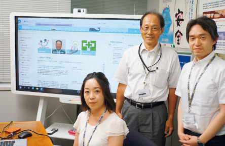 図版：「Ywai！」の画面をバックにする横浜支店管理部総務グループ（情報システム担当）のメンバー