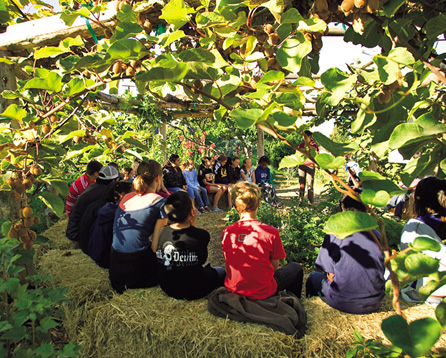 写真：農園内にある屋外教室。藁でつくった円形ベンチに座って先生の話に聞き入る生徒たち