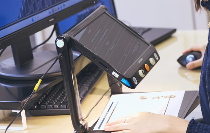 視覚障がいのある社員が使用する、手元の資料をモニターに大きく映し出す卓上型拡大読書器の写真