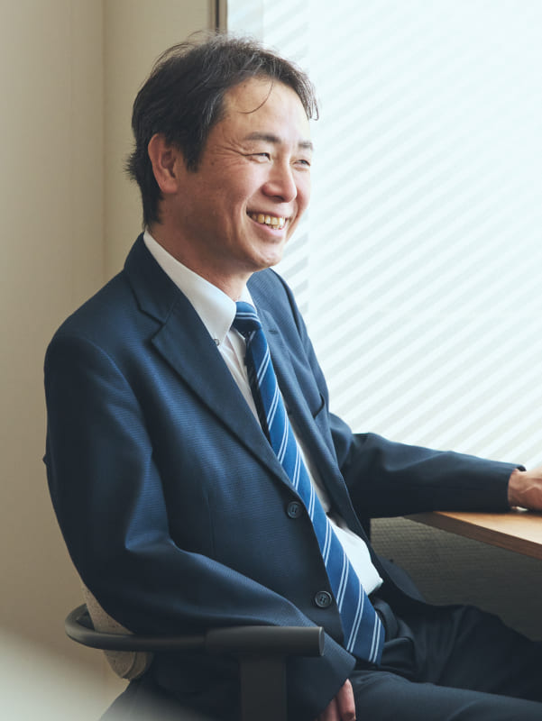 清潔感のあるオフィスで、穏やかな表情を浮かべる右上肢障がいの男性社員の写真