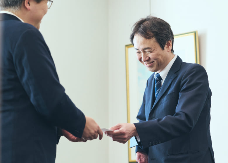 片手ながらも、明るく微笑みながら名刺交換をする障がいのある社員の写真