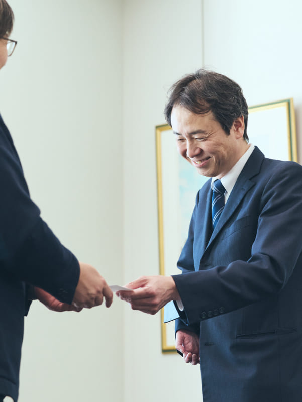 片手ながらも、明るく微笑みながら名刺交換をする障がいのある社員の写真