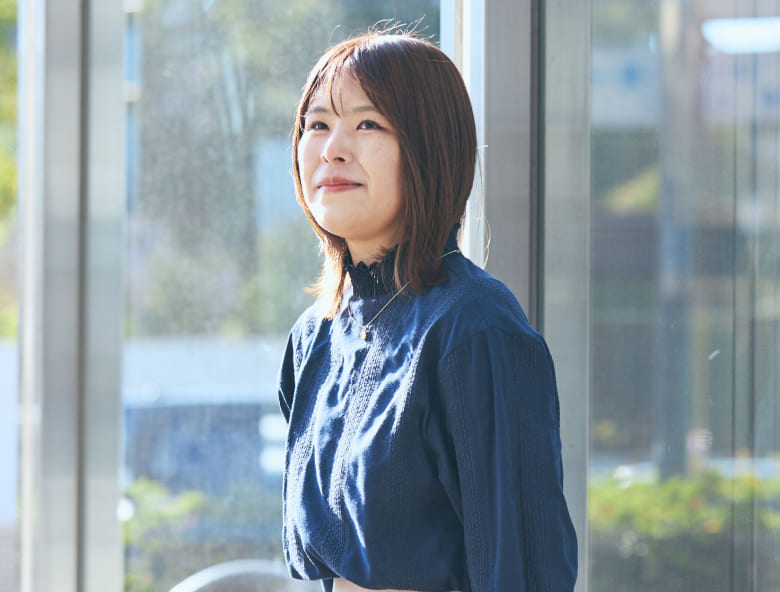 穏やかな光を浴び、未来を見据えるような優しい表情を浮かべる視覚障がいの女性社員の写真