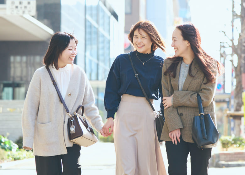 屋外にて、同僚に腕を貸してもらいながら安心して歩を進める女性社員の写真