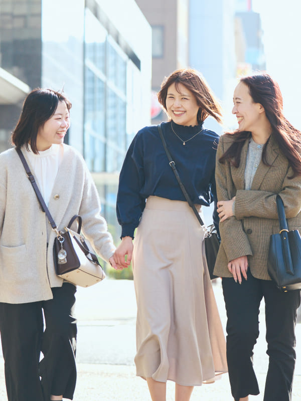 屋外にて、同僚に腕を貸してもらいながら安心して歩を進める女性社員の写真