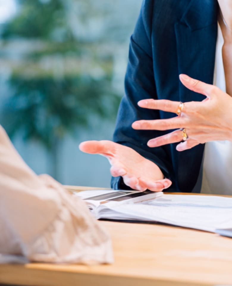 デスクで資料を広げ、落ち着いた雰囲気で面談を行っている様子の手元イメージ写真
