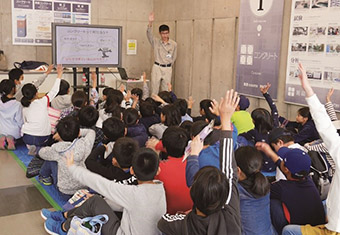 図版：コンクリートに関するクイズに元気よく挙手する児童たち