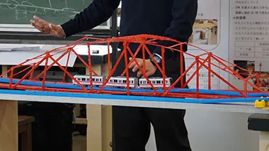 橋の模型に玩具の電車を走らせ実験する班