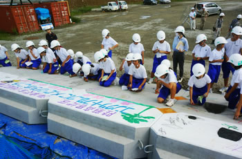 図版：コンクリートブロックにメッセージを書き入れる陸前高田市立第一中学校の生徒たち