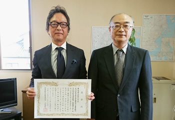 図版：柴崎署長（写真右）から岡野所長（写真左）への表彰状贈呈