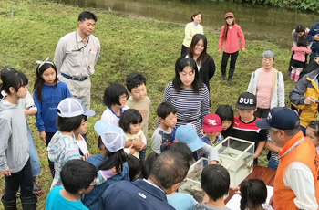 図版：漁協の担当者から山女魚と岩魚の違いなどの説明を受ける参加者