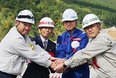 図版：がっちりと握手を交わす左から池田所長、佐々木村長、村山所長、奈須野所長