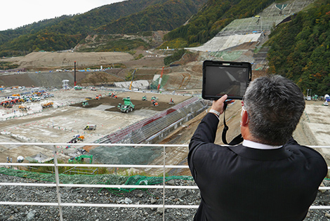 図版：展望デッキからは施工中の堤体が見下ろせ、タブレットをかざすと完成後の堤体が現れる