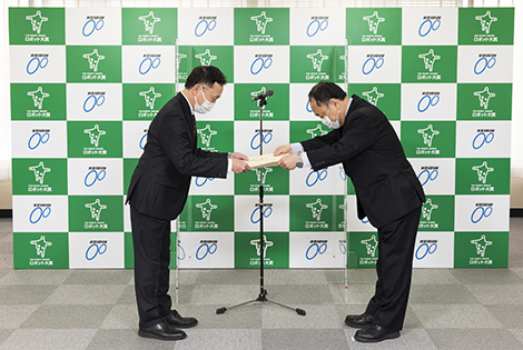 図版：川村審査特別委員長から表彰状を受け取る植木機械部長（左）