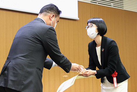 図版：森戸選考委員よりトロフィーを授与される小野担当部長（右）