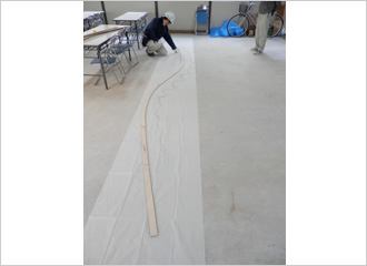 写真：一重屋根唐破風部の軒先の原寸型板を確認しています｡解体前に和紙ヘカーボンで型（拓本）を取り､その型に合せて型板を作成しました｡