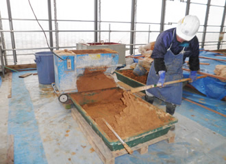 写真：平瓦葺き用の葺土を練合せ中です。解体した時の瓦葺き土を再利用して葺き直しますが、既存の土は粘りが強すぎるため、川砂、ワラ、漆喰等を葺く用途に応じて配合・調整します。